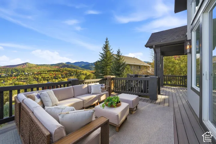 Expansive outdoor deck with composite decking and dark railings, featuring a wall-mounted exterior light fixture and an overhead eave