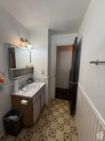 Pedestal sink vanity with a light-toned countertop, framed mirror, and patterned flooring