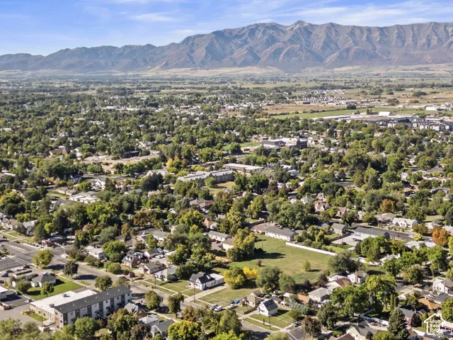 Expansive mountainous backdrop framing a verdant landscape of mature trees and residential properties