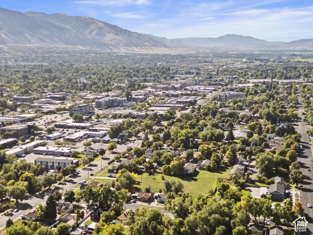 Expansive aerial perspective showcasing a developed community with abundant mature trees and mountainous terrain