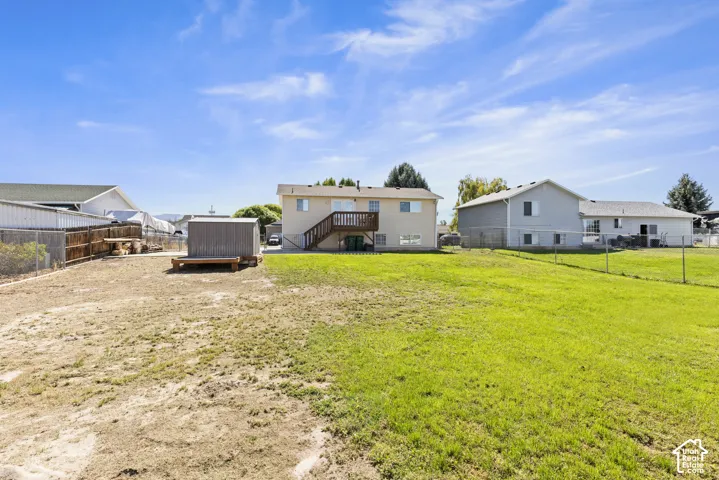 Expansive backyard featuring a green lawn, chain-link fencing, and a detached storage shed
