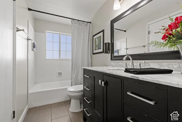 Bathroom featuring a black vanity with a light-colored countertop, an integrated sink, and an expansive wall mirror