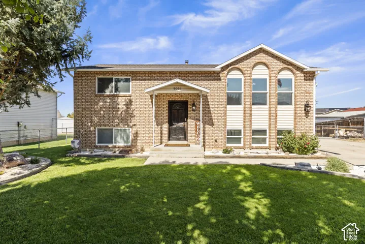 Brick facade with arched window accents, covered entryway, and front yard landscaping