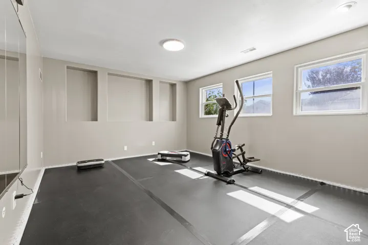 Recessed wall shelving, multiple windows, overhead lighting, and dark rubberized flooring