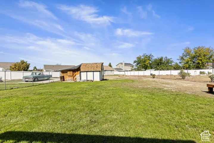 Expansive fenced yard with a manicured lawn area and a storage shed featuring a gambrel roof