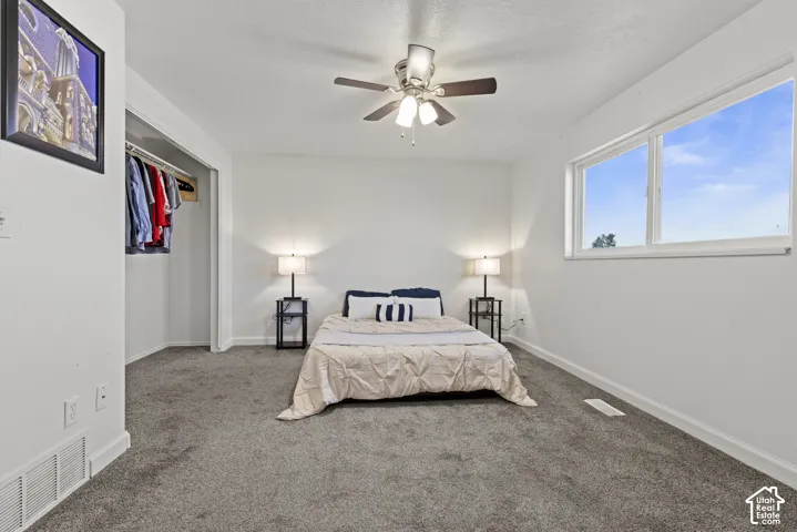 White walls, gray carpet, and a ceiling fan with integrated lighting