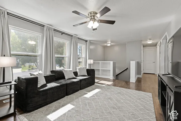 Hardwood-finish flooring throughout, ceiling fan with integrated lighting, multiple windows, built-in shelving, and recessed lighting