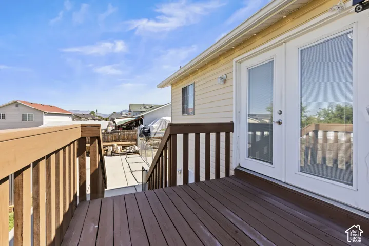 Outdoor deck with wood-finish flooring and railings, featuring white double glass-panel doors