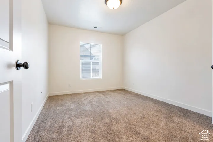 Carpeted room with a single window, white walls, and a ceiling-mounted light fixture