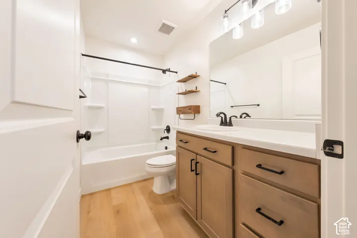 Contemporary bathroom featuring a light wood-finish vanity with matte black hardware, white countertop, and a built-in tub with a shower