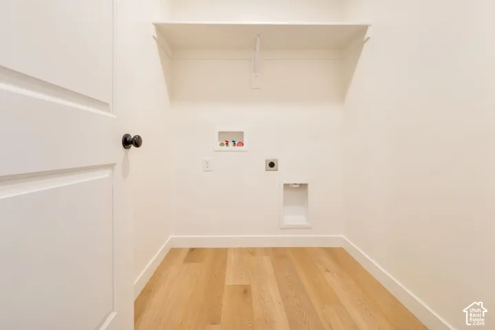 Utility area featuring wood-finish flooring, a wall-mounted shelf, and appliance hookups