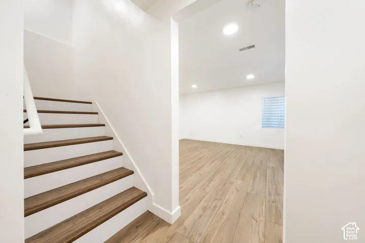 Wood-finish flooring, recessed lighting, white walls, and a window with blinds