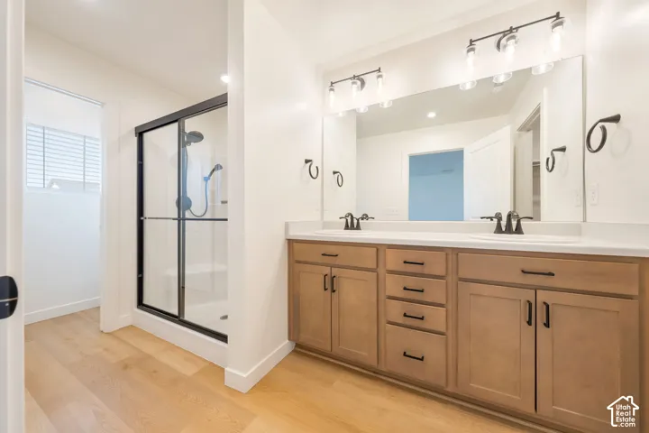 Dual vanity with light wood-finish cabinetry, solid surface countertops, and matte black fixtures