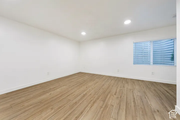 Recessed ceiling lighting, wood-finish flooring, white walls, and a window with blinds