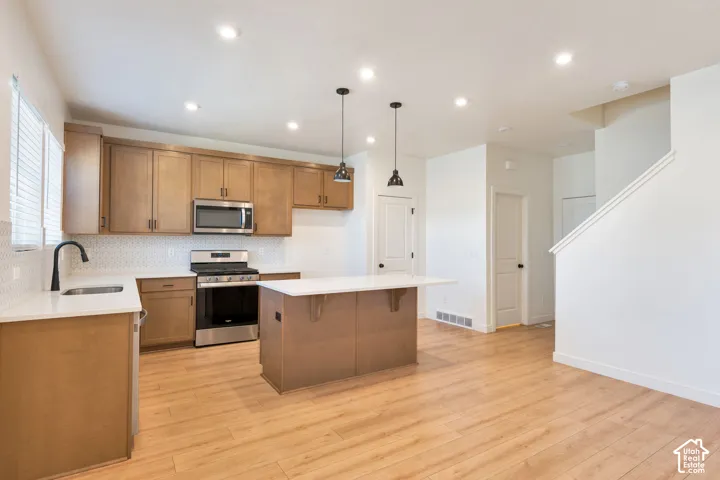 Kitchen featuring wood-finish cabinetry, stainless steel appliances, white countertops, and a hexagonal tile backsplash
