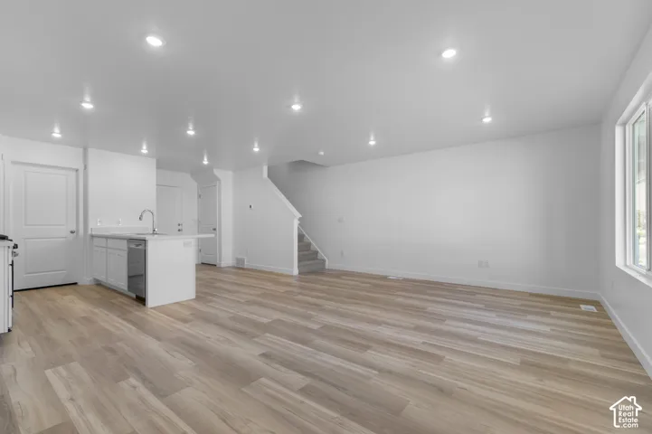 Open-concept living area featuring wood-finish flooring, recessed lighting, and a kitchen island with integrated sink