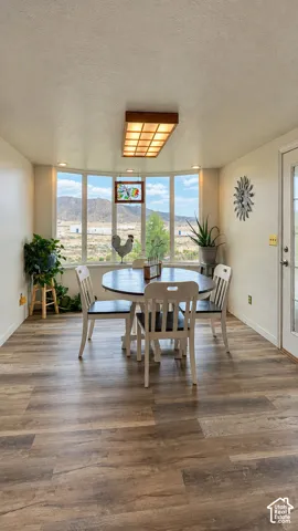 Bay window with mountain scenery and natural light, wood-finish flooring, and recessed lighting