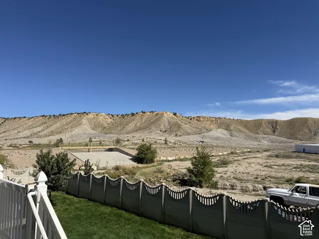 Expansive desert landscape with natural terrain, surrounded by a decorative fence with scalloped detail, and a manicured lawn