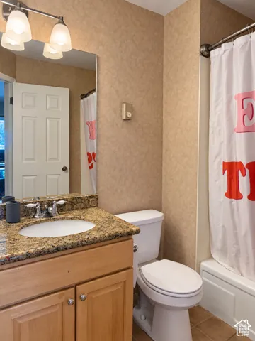Bathroom featuring a wood-finish vanity with a granite-style countertop, undermount sink, and a framed mirror