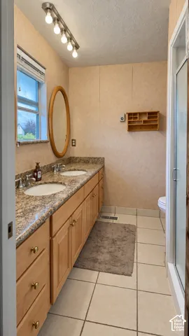 Double vanity with a speckled countertop, dual undermount sinks, and wood-finish cabinetry