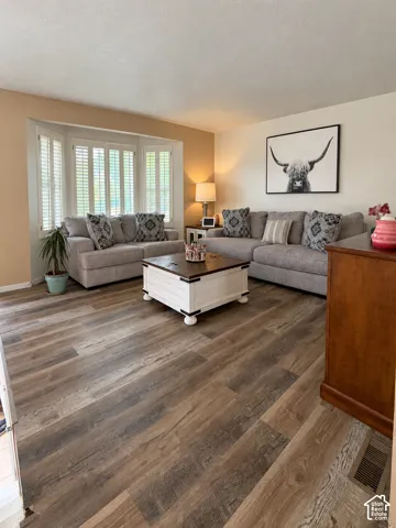 Bay window with louvered shutters, wood-finish flooring, and recessed lighting