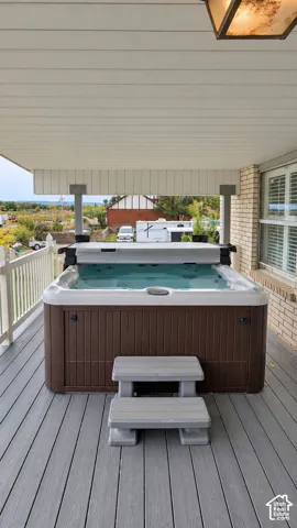 Covered outdoor spa with composite decking, white railing, and brick exterior