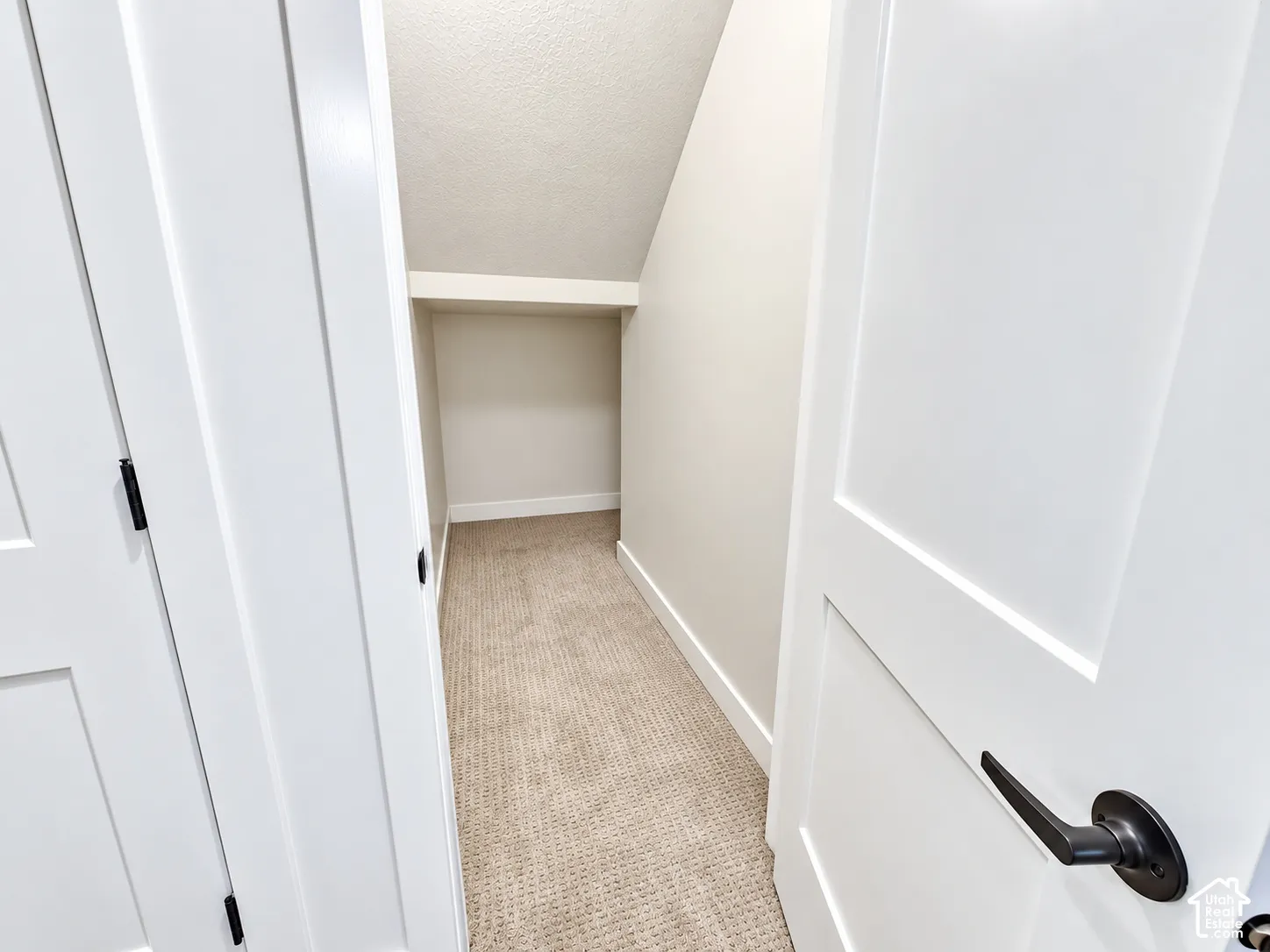 Recessed storage area with neutral carpeting, white baseboards, and a built-in shelf