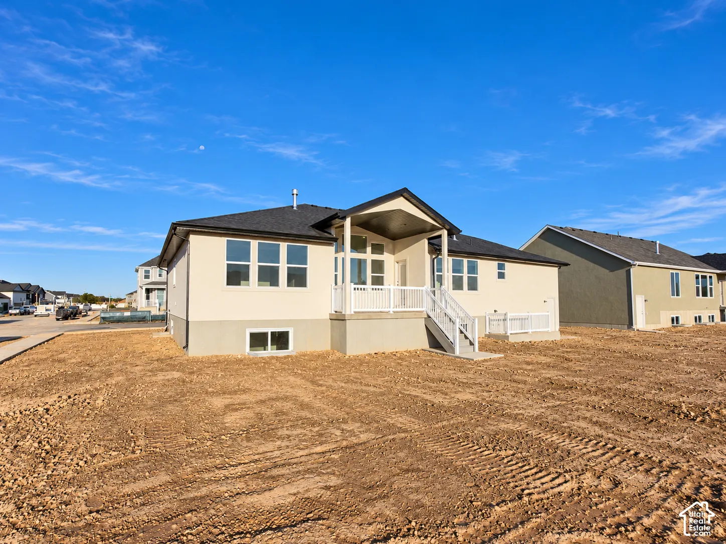Rear exterior featuring a covered patio, white railings, and a two-story design with a lower-level window