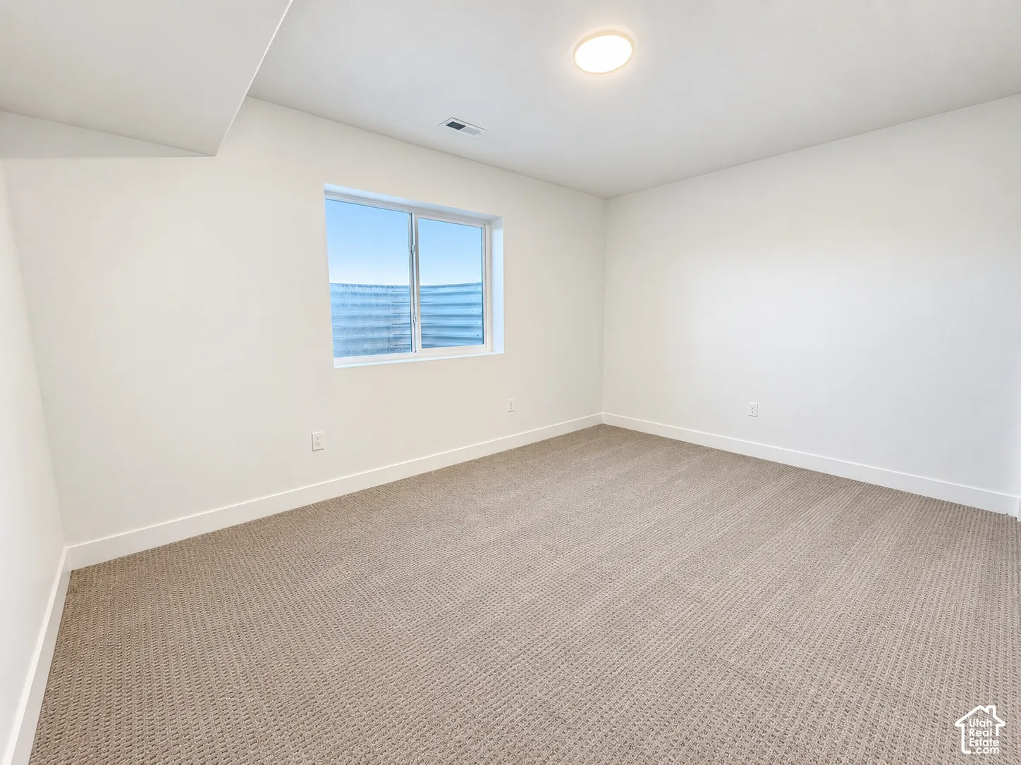 Recessed window with white trim, light-colored walls, and textured carpet flooring