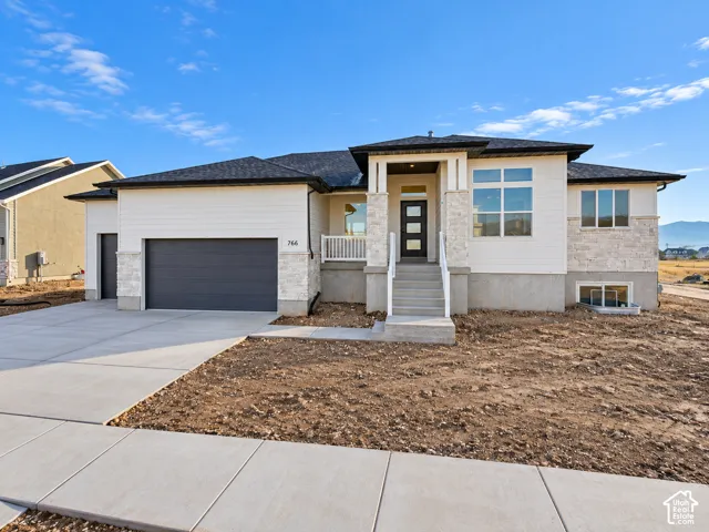 Contemporary exterior with white siding and stone accents, a multi-pane front door, and an attached two-car garage