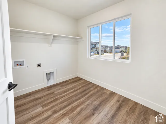 Wood-finish flooring with white baseboards, a built-in white shelf, and a large window