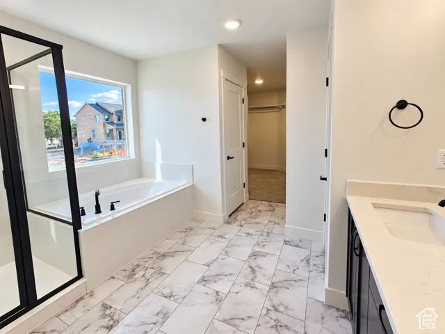 Contemporary bathroom with marble-finish tile flooring, a built-in soaking tub, and a shower with a black-framed glass enclosure