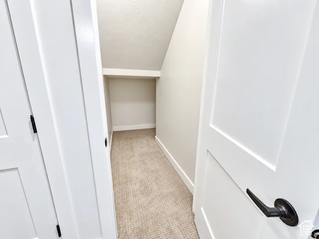 Recessed storage area with neutral carpeting, white baseboards, and a built-in shelf
