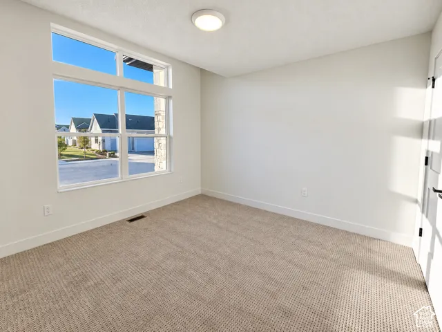 Wall-to-wall carpeting, large multi-pane window, flush-mount ceiling light, white painted walls, and white trim