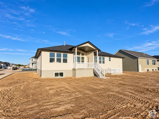 Rear exterior featuring a covered patio, white railings, and a two-story design with a lower-level window