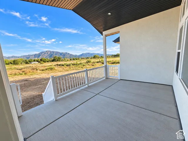 Covered concrete patio with white railing and mountain scenery