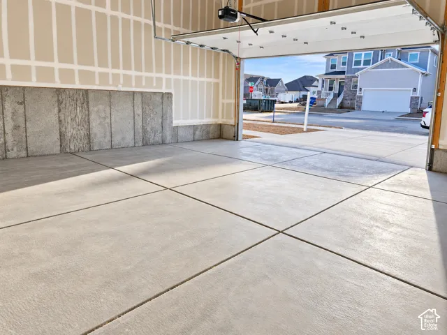 Spacious garage with a concrete floor, an overhead door, and concrete panel wall sections
