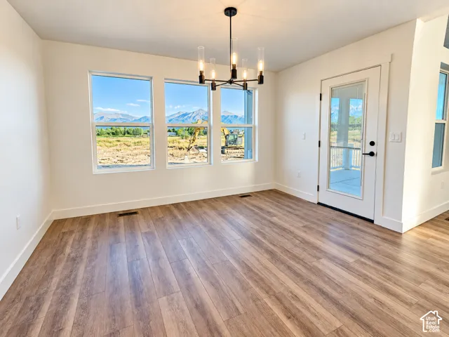 Wood-finish flooring, multiple windows, contemporary chandelier, white trim throughout, and a glass-paneled door