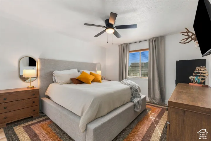 Recessed lighting, ceiling fan with integrated light, upholstered bed frame, window with blinds, and drapery rods