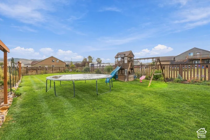 Expansive lawn area with perimeter fencing, featuring a play structure with slide and swing set