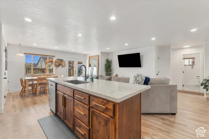 Kitchen island with wood-finish cabinetry, light-toned countertop, and integrated stainless steel sink