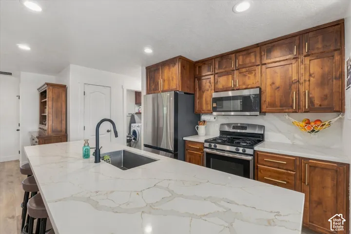 Spacious kitchen with a large island, wood-finish cabinetry, stainless steel appliances, and light-colored countertops