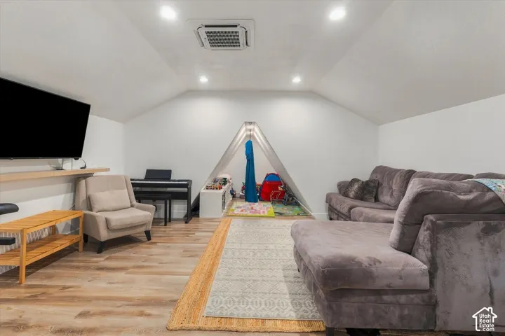Vaulted ceilings, recessed lighting, wood-finish flooring, and built-in shelving