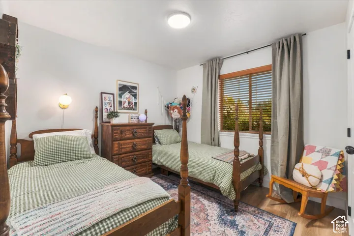 Bright interior space featuring a window with wood blinds, wood-finish flooring, and a flush-mount ceiling light