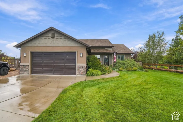 Attached two-car garage, stone accent detailing, a gabled roofline, concrete driveway, and mature landscaping