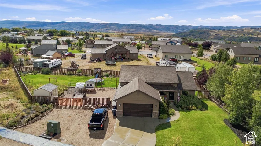 Single-family residence featuring an attached two-car garage, partial stone facade, and a shingled roof