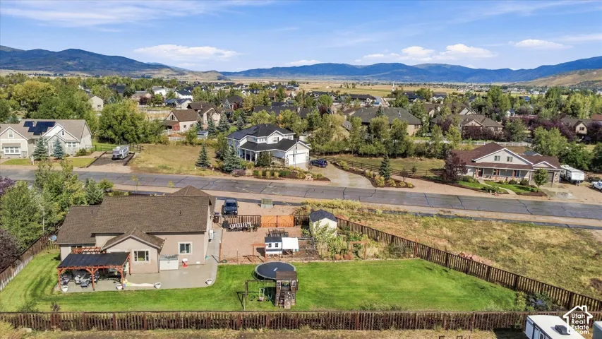 Expansive backyard featuring a manicured lawn, covered patio, and wood fencing
