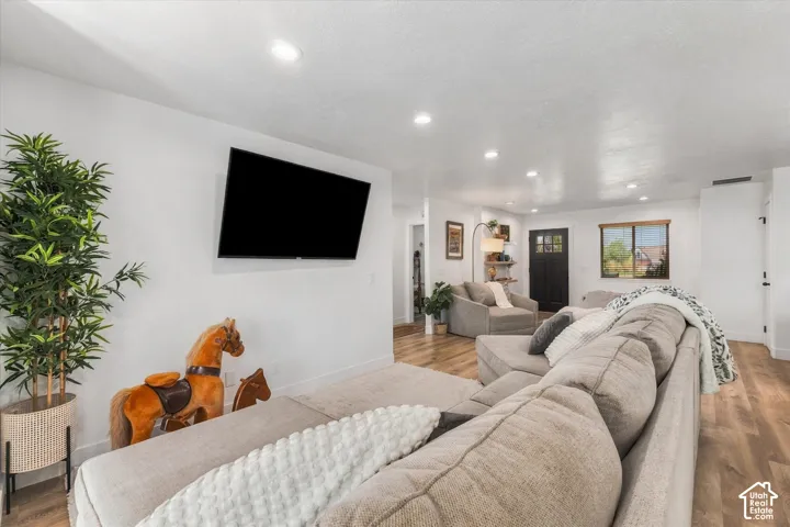 Open-concept living area featuring recessed lighting, wood-finish flooring, and a mounted display area