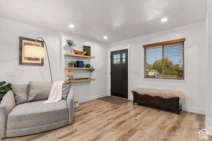 Wood-finish flooring throughout, recessed lighting, and a dark-paneled entry door with clear glass inserts