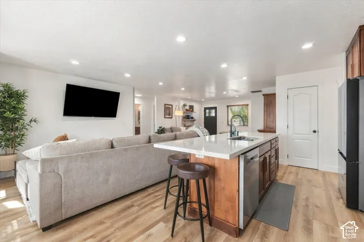 Open-concept living space featuring wood-finish flooring, recessed lighting, and a kitchen island with seating